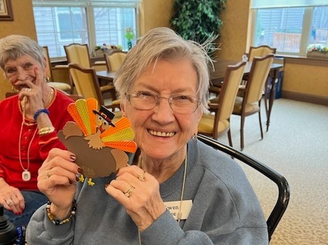 senior woman holding up a turkey arts and craft project